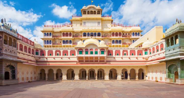 Colourful inner courtyard of Jaipur City Palace under a partly cloudy sky.