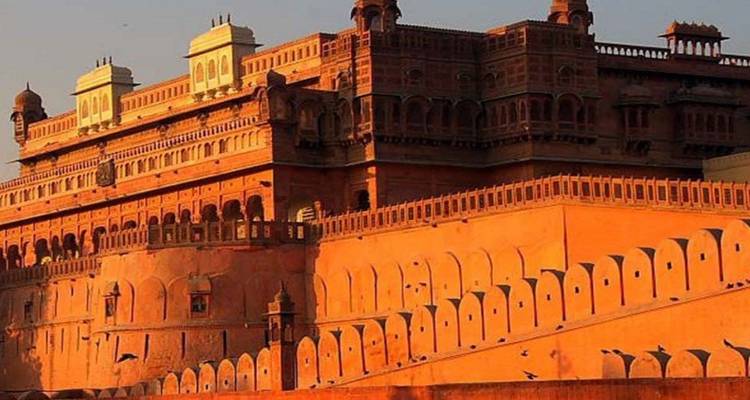 Sunlit orange sandstone fort with long battlements and decorative windows.