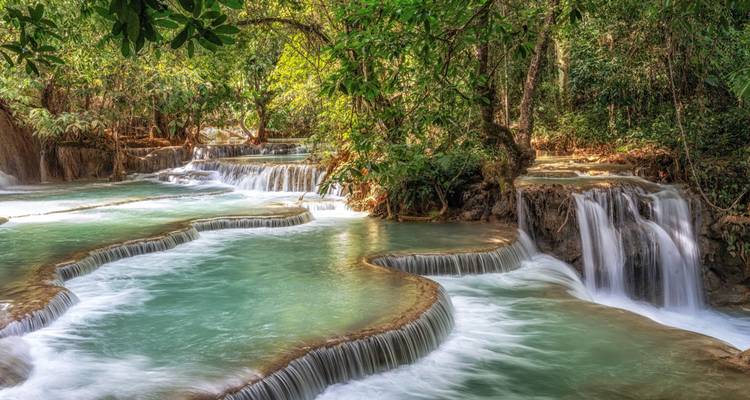 Turquoise tiered pools cascading through lush jungle at a tropical waterfall