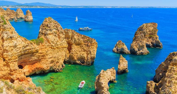 Dramatic golden cliffs and sea stacks rising from turquoise waters on the Algarve coast, Portugal.