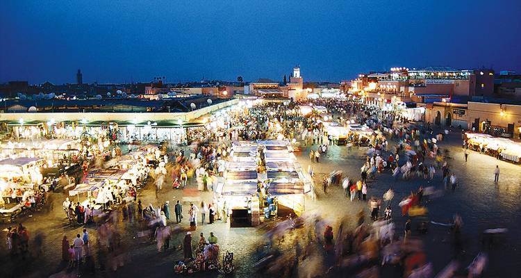 Vue nocturne de la place animée Jemaa el-Fnaa à Marrakech remplie du mouvement flou des foules et des étals.