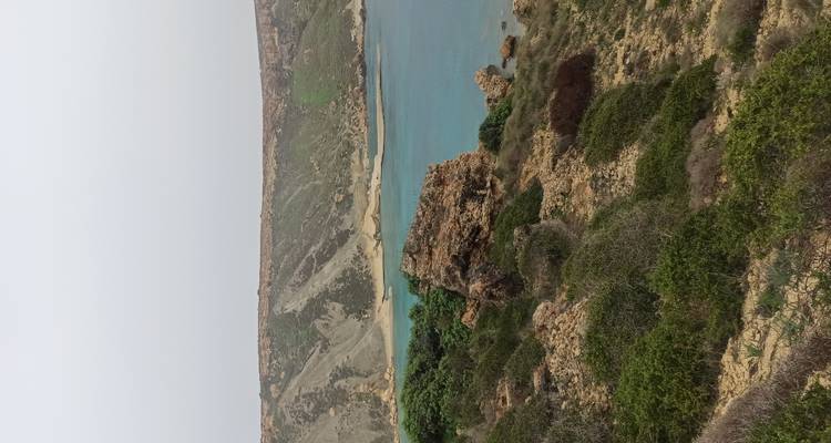 Panoramisch uitzicht op de turquoise baai omringd door droge landtongen en scrublandvegetatie.