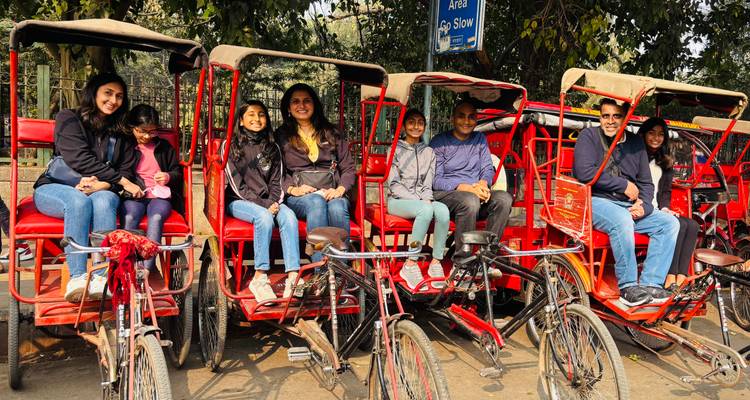 Families sit together on bright red cycle rickshaws ready for a city tour.