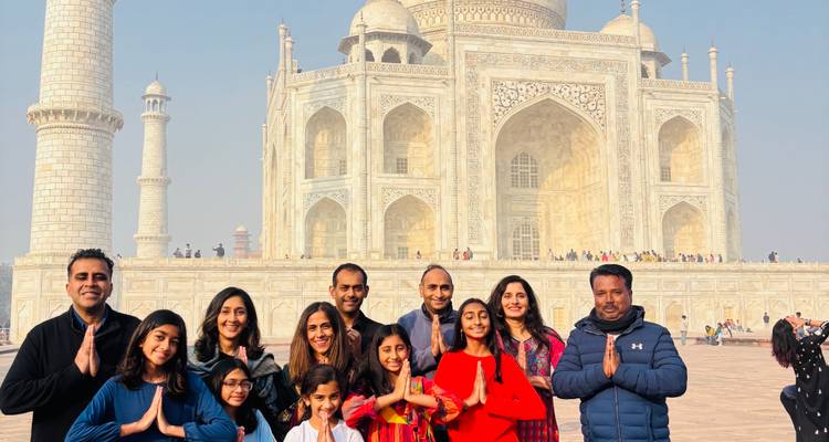 Tour group stands praying-style before the gleaming marble façade of the Taj Mahal.