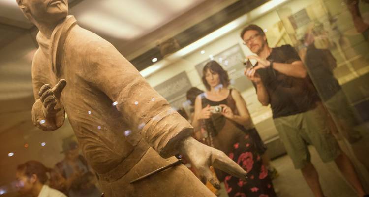 Visitantes del museo fotografiando una exhibición de Guerreros de Terracota detrás de vidrio
