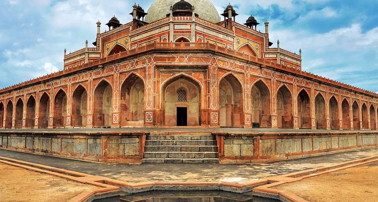 La Tumba de Humayun con su ornamentada arenisca roja y mármol blanco enmarcada por el cielo azul, mostrando la arquitectura simétrica mogol.