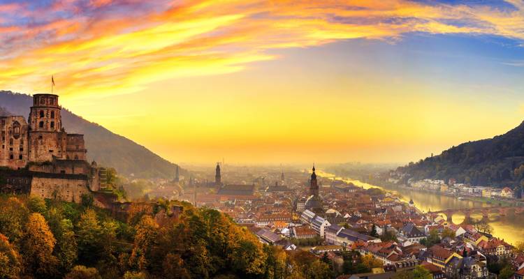 Dramatisches Sonnenaufgangspanorama über Heidelberg mit Schlossruinen, Kirchentürmen und farbenfrohem Himmel.