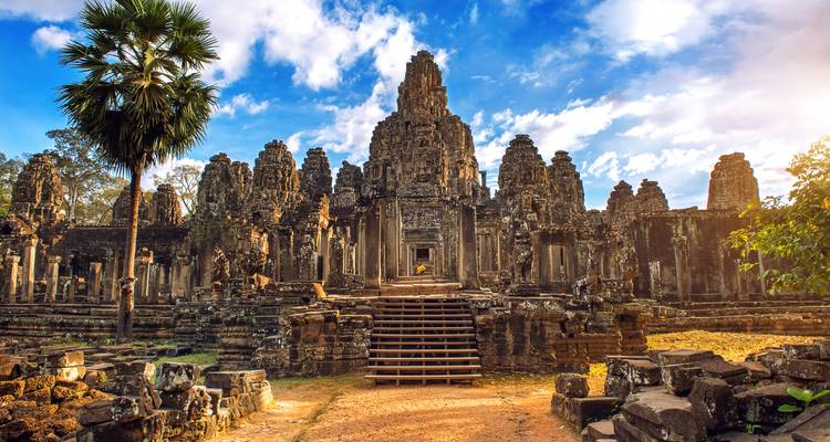 Les visages de pierre spectaculaires et les tours du temple Bayon illuminés par la lumière chaude de fin d'après-midi sous des nuages épars.
