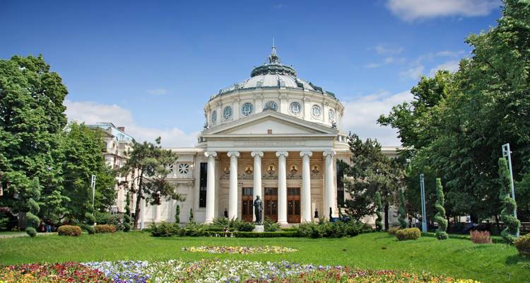 Salle de concerts Athénée roumain avec jardin de fleurs et ciel bleu.
