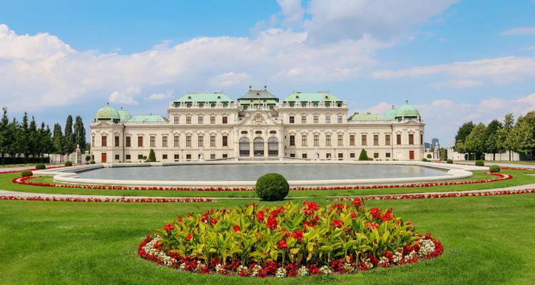 Baroque Upper Belvedere Palace with symmetrical gardens and reflective pond under bright skies in Vienna.