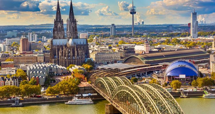 Vista aérea detallada de la Catedral de Colonia, la estación de trenes y el Puente de Hohenzollern atravesando el Rin.