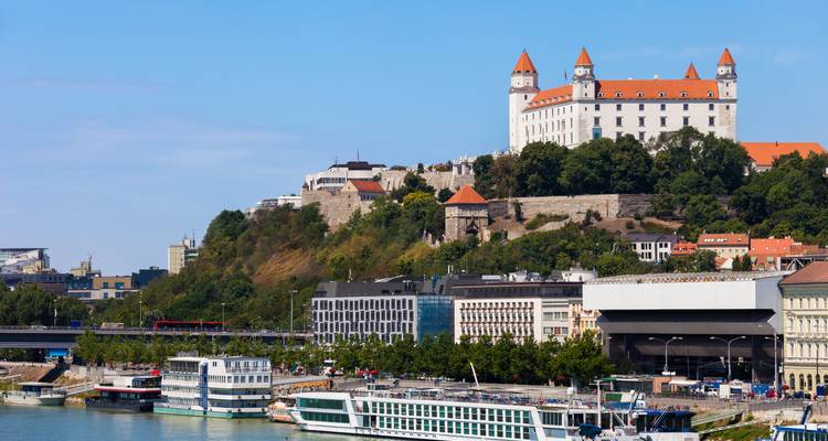 Bratislava Castle perched above Danube River and modern city quayside.