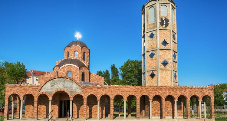 Brick Orthodox church and clock tower with blue sky in Novi Sad.