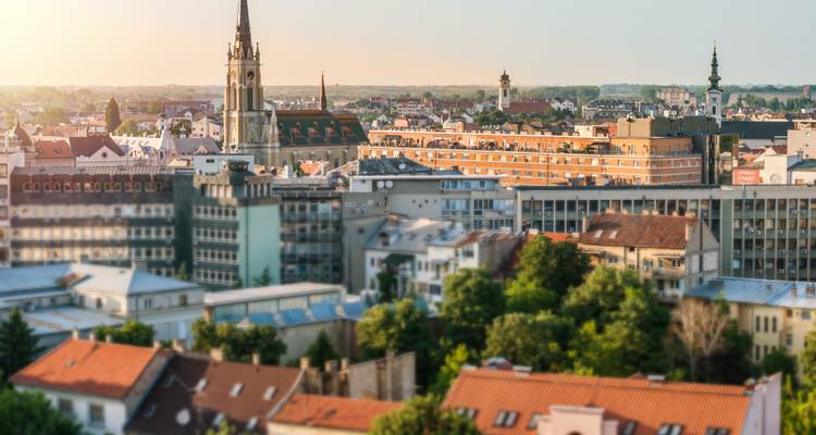 Tilt-shift style aerial view of Novi Sad skyline at warm sunset.