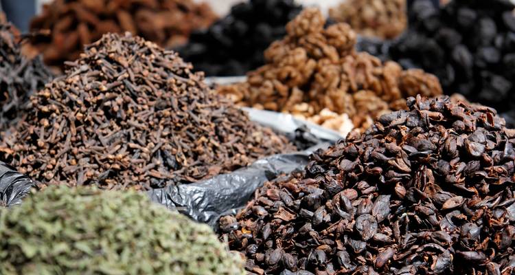 Bergen assorteerde kruiden en gedroogde kruiden opgestapeld hoog in een openluchtmarkt kraam.