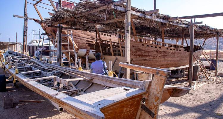 Bateau dhow traditionnel en construction dans un chantier naval en bois à ciel ouvert à Sur.