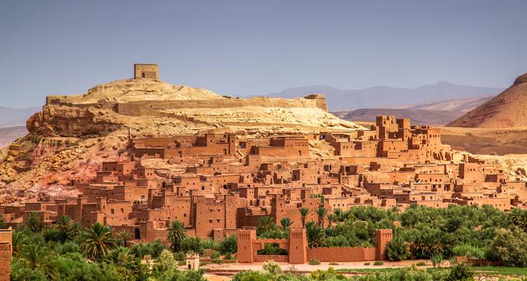 Large panorama de la kasbah perchée d'Aït Benhaddou et des palmiers environnants.