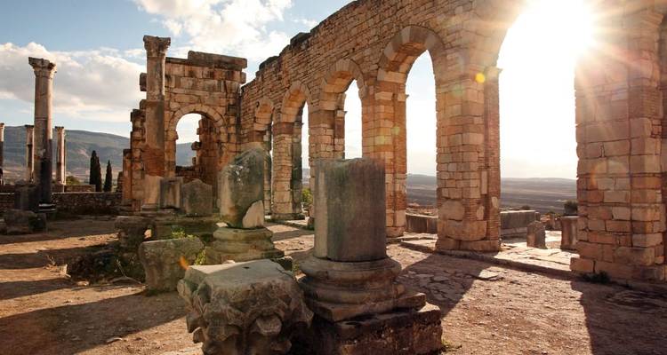 Les arches de pierre baignées de soleil des ruines romaines antiques avec des rayons de lumière traversant