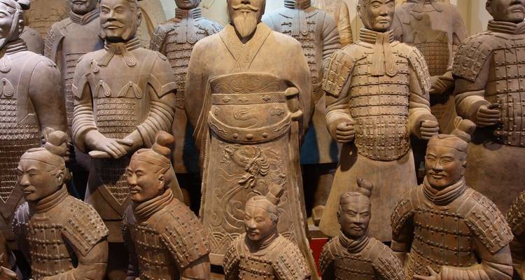 Row of Terracotta Warrior statues in a museum setting, showcasing detailed ancient armor.