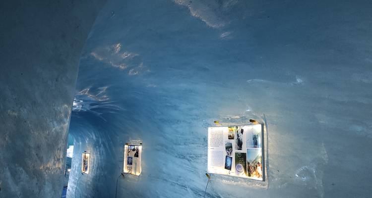 Paroi de tunnel de glace bleue avec des panneaux d'information illuminés montés le long de la courbe.