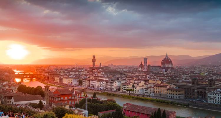 El horizonte de Florencia al atardecer con la luz dorada iluminando el río Arno y los monumentos históricos.