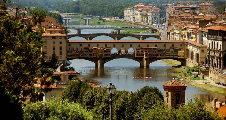 Daytime cityscape of Florence featuring the Ponte Vecchio spanning the Arno River.