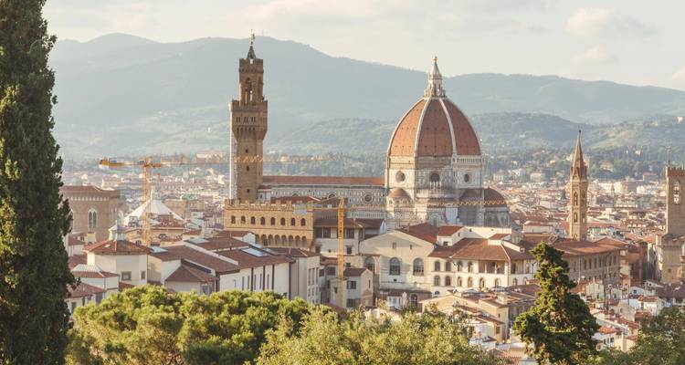 Softly lit view of Florence Cathedral and city rooftops framed by distant hills.