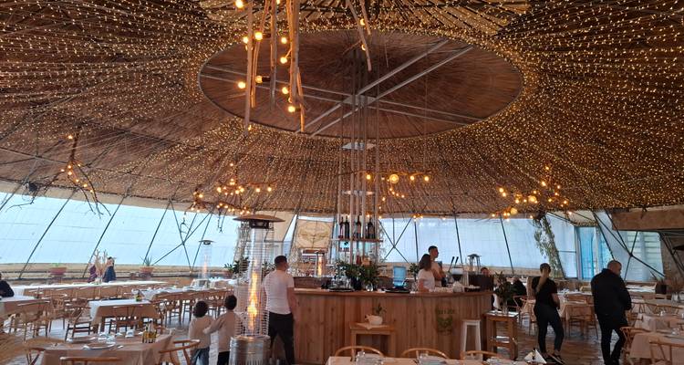 Geräumiges kreisförmiges Restaurant mit Holzdekor und hängenden Lichterketten, Gäste speisen im Inneren