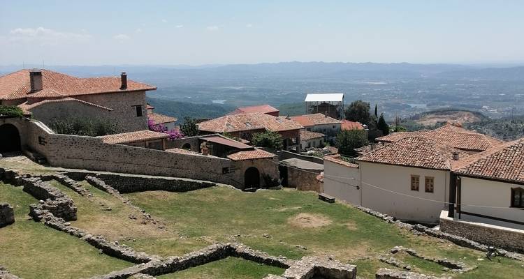 Vista panorámica de los tejados de tejas y ruinas de piedra de Krujë con llanuras extensas a lo lejos.