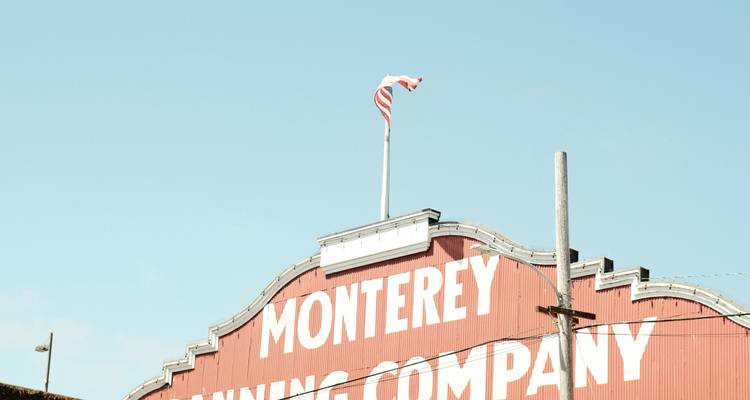 Façade supérieure de l'enseigne de la Monterey Canning Company avec un drapeau américain sur fond de ciel bleu.