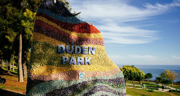 Panneau en mosaïque de pierre colorée portant l'inscription « Düden Park » avec la mer et les arbres au-delà