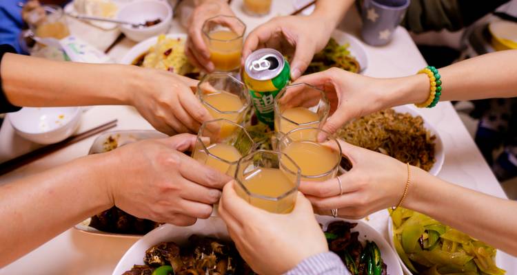 Groupe d'amis trinquant les verres lors d'un toast de célébration autour d'une table de nourriture