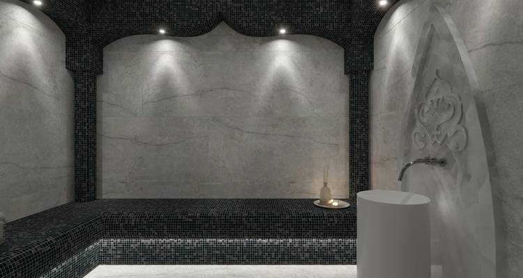 Een moderne grijze marmeren Turkse hammam ruimte met zacht ingebouwd licht en een waterbak.