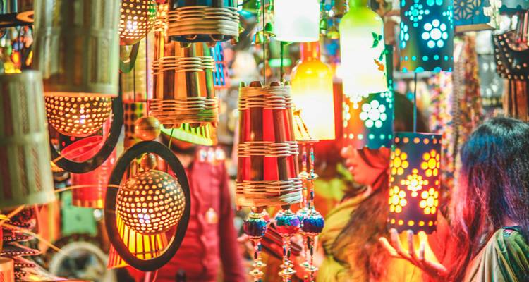 Coloridas lámparas colgantes y artesanías creando una escena de mercado vibrante por la noche.
