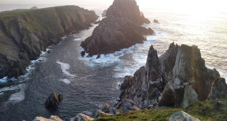 Des pics rocheux dentelés et un littoral rocailleux illuminés par le soleil bas du soir