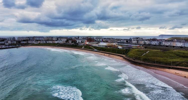 Vue aérienne de la ville de Portrush, de la plage et des vagues qui se brisent sous des nuages menaçants