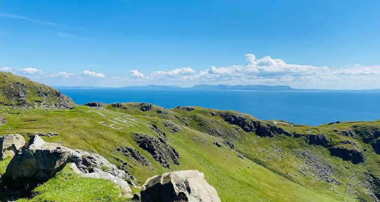 Collines côtières verdoyantes avec des pierres blanches formant EIRE surplombant la mer bleue