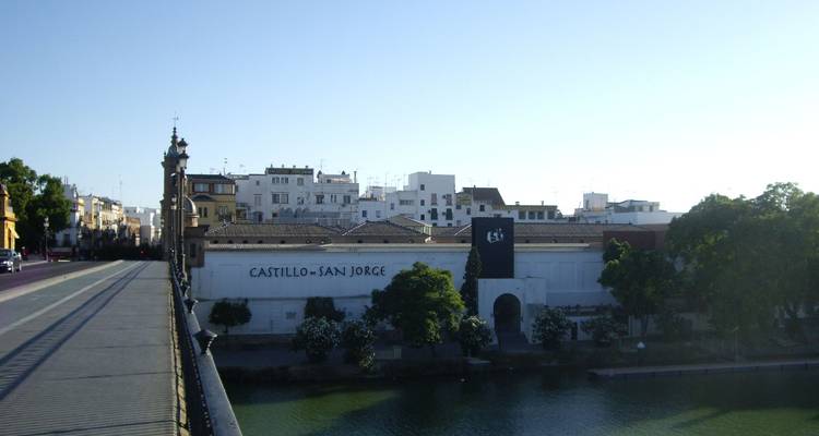 Vue depuis un pont vers le bâtiment blanc et bas du Castillo San Jorge le long du fleuve à Séville.