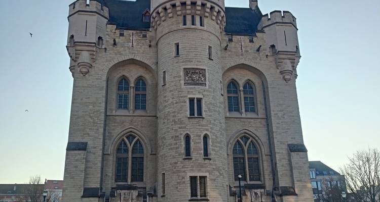 Stone medieval gate-house tower with turrets against a pale sky.