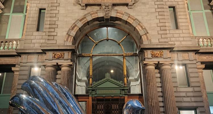Stone entrance of a grand 19th-century building with metal sculpture in foreground.