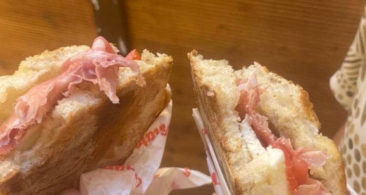 Close-up of Italian sandwich halves filled with prosciutto and cheese.