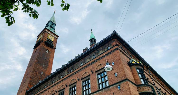 Tour de l'hôtel de ville de Copenhague en brique avec horloge et flèche encadrées contre un ciel nuageux