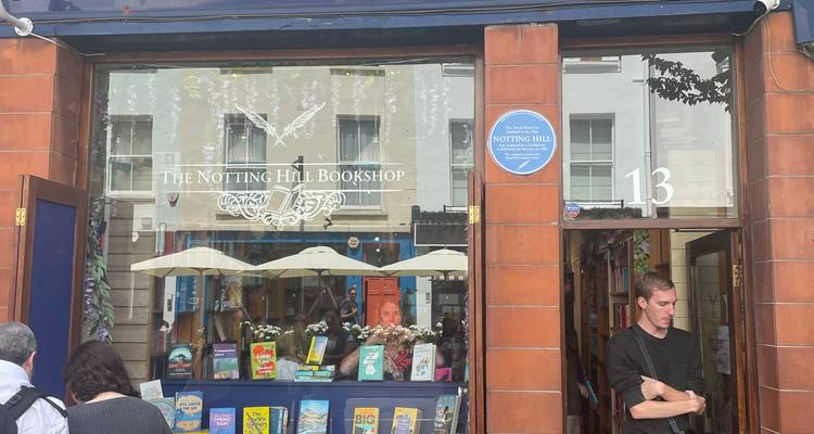 Facade of The Notting Hill Bookshop with colorful books displayed in the window and a visitor standing nearby