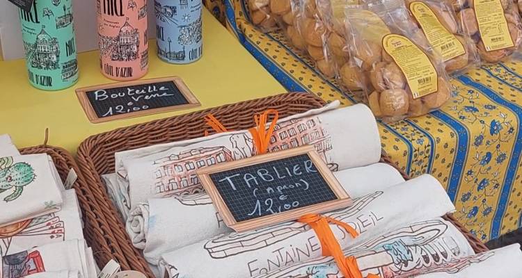 Étal avec des souvenirs provençaux, des serviettes et des biscuits arrangés sur une table de marché à thème jaune.