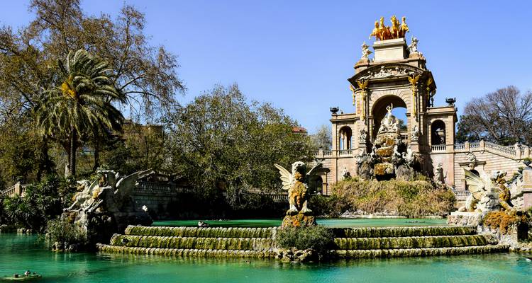 Étang turquoise baigné de soleil et sculptures ornementales de la fontaine Cascada Monumental de Barcelone entourées de verdure