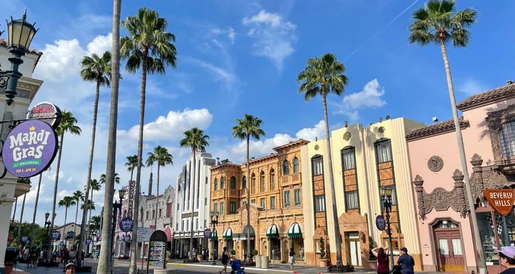 Façade de rue colorée à l'intérieur d'Universal Studios Orlando, bordée de palmiers et de visiteurs