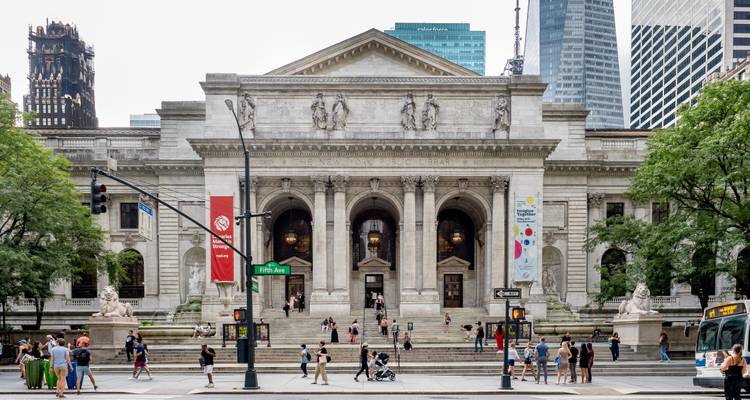 Front façade of the New York Public Library with grand stairs and lion statues bustling with visitors.