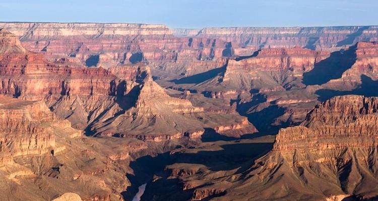 Les couches ensoleillées du Grand Canyon s'étendant au loin avec des ombres profondes.
