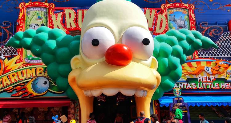Entrée vibrante de Krustyland avec une géante tête de Krusty le Clown dans un parc à thème, foules entrant ci-dessous.
