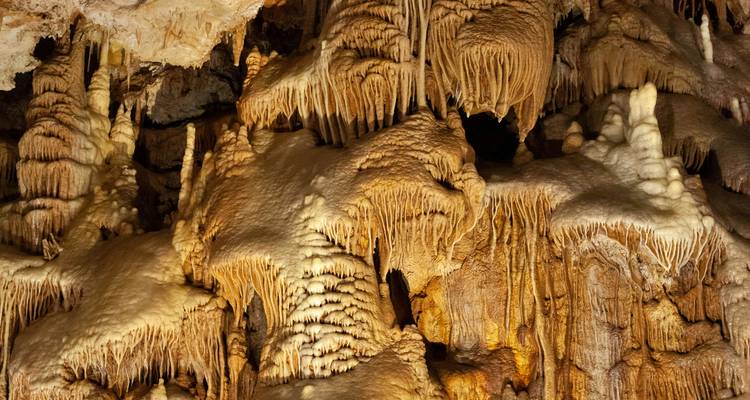 Vue détaillée rapprochée des formations complexes de travertin de grotte à la lumière chaude.
